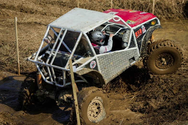 a red and white buggy driving through a muddy field, by Jeffrey Smith, flickr, auto-destructive art, action sports photography, girl, maxxis, crawling