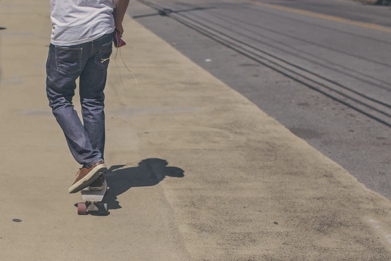 a man riding a skateboard down a sidewalk, a picture, unsplash, shaded, denim, wide shot photo, widescreen