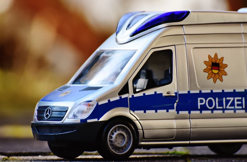 a toy police van parked on the side of the road, by Adam Marczyński, trending on pixabay, photorealism, german, zoomed in, thick blue lines, photorealism. trending on flickr