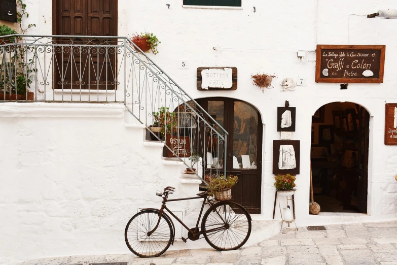 a bicycle parked in front of a white building, folk art, italian style, lightbox, rustic setting, crafts and souvenirs