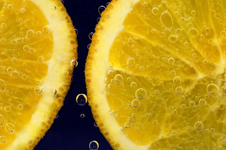 two slices of lemon sitting next to each other, a macro photograph, digital art, water particules, 4k high res, yellow-orange, energy drink