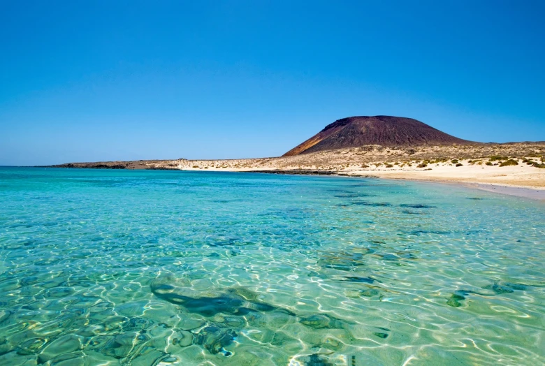 a body of water with a mountain in the background, a photo, by Juan O'Gorman, shutterstock, white beaches, laputa, extremely clear and coherent, the photo shows a large