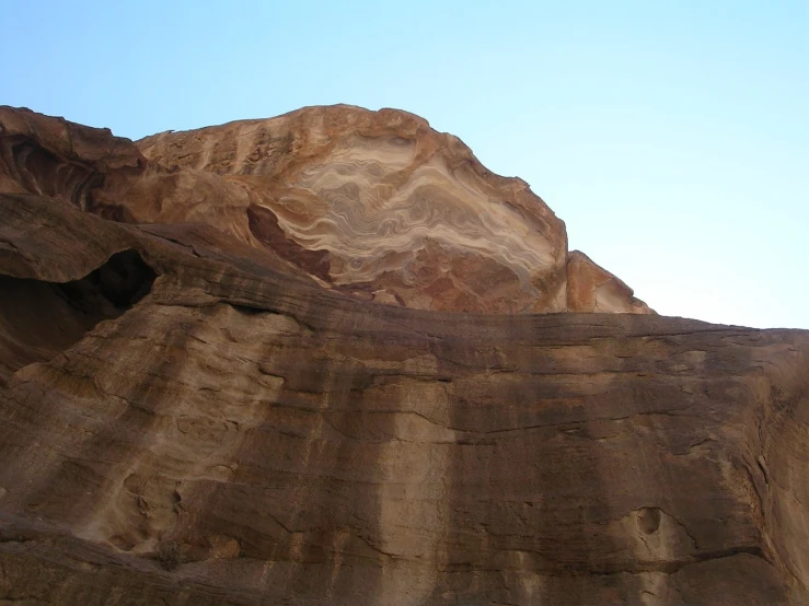 a large rock formation with a blue sky in the background, flickr, les nabis, egypt, detailed veiny muscles, flaming mountain, cave wall