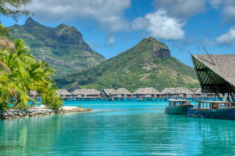 a couple of boats that are in the water, a picture, by Jay Hambidge, shutterstock, hurufiyya, thatched roofs, behind that turquoise mountains, 😃😀😄☺🙃😉😗, polynesian style