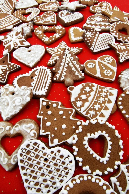 a table topped with lots of cookies covered in icing, a photo, pexels, folk art, red brown and white color scheme, beautiful shapes, bells, hearts