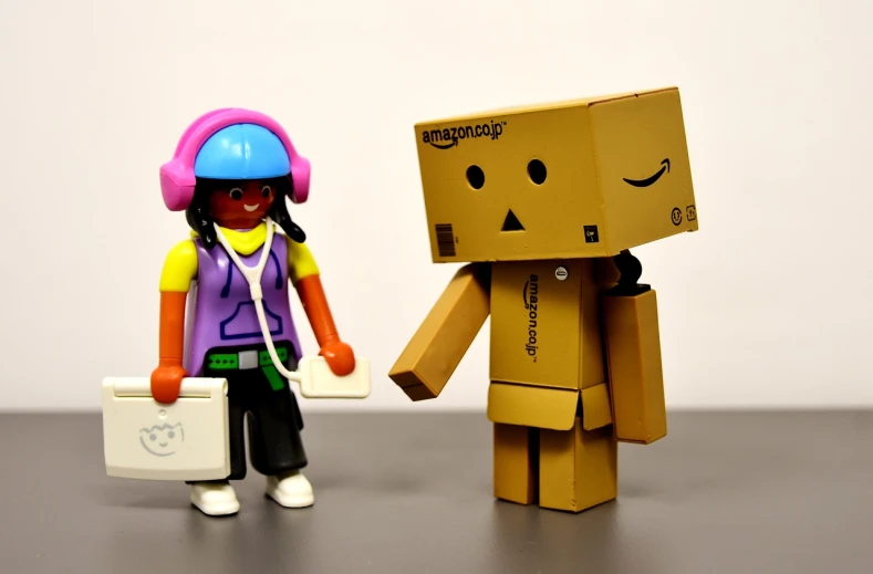 a couple of figurines standing next to each other, a picture, by Randy Post, flickr, figuration libre, robot made of a cardboard box, amazon, speakers, having a good time