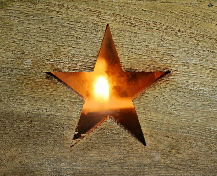 a close up of a metal star on a wooden surface, a photo, folk art, fire light, museum quality photo, high res photo, keyhole