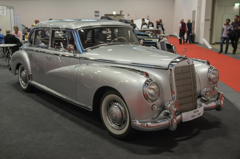 a silver car on display at a car show, a pastel, by Oskar Lüthy, trending on pixabay, bauhaus, mercedez benz, super long shot, 3 / 4 wide shot, coronation