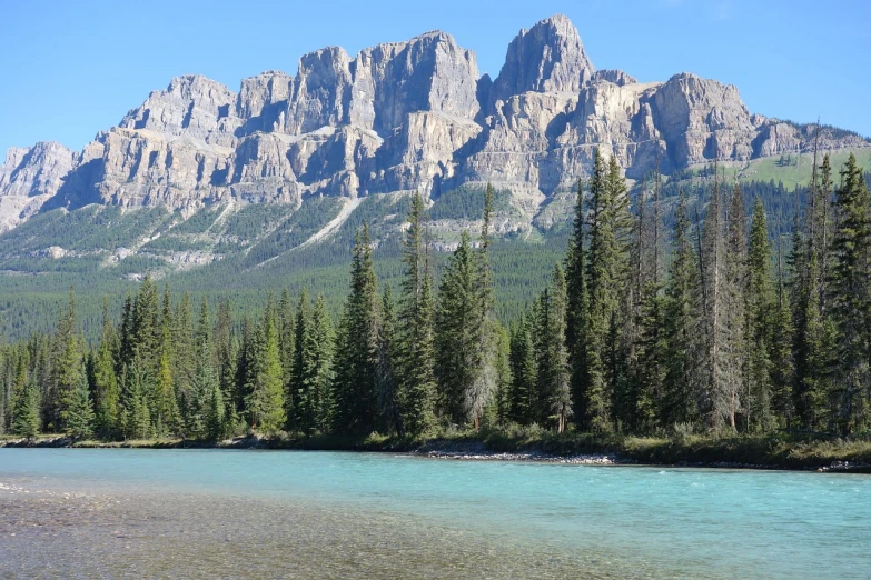 a body of water with a mountain in the background, tall stone spires, blue river in the middle, canada, wikimedia