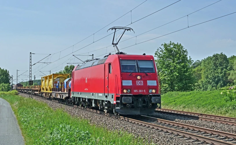 a red train traveling down train tracks next to a lush green field, a portrait, by Hans Schwarz, flickr, electric, maintenance photo, on a bright day, 1 male