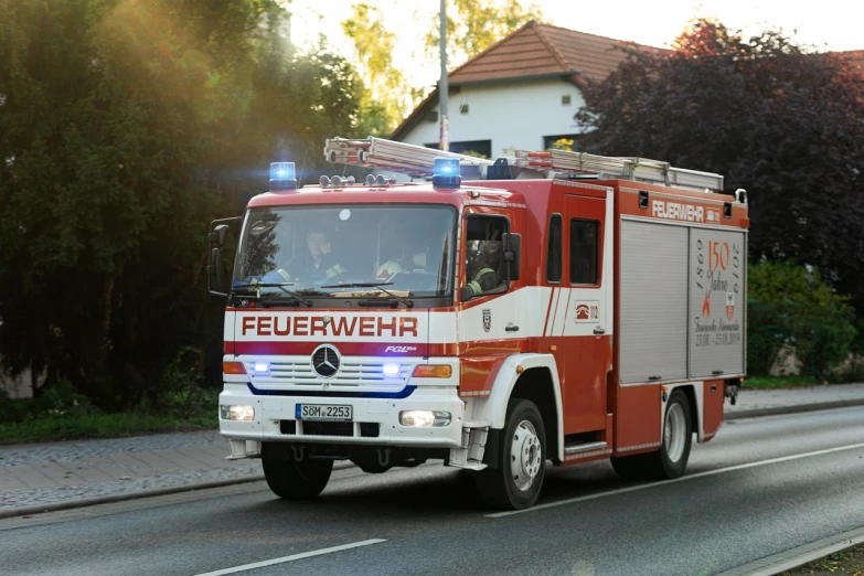 a red and white fire truck driving down a street, a picture, by Hans Schwarz, shutterstock, figuration libre, detailed zoom photo, gas, hannover, green fire