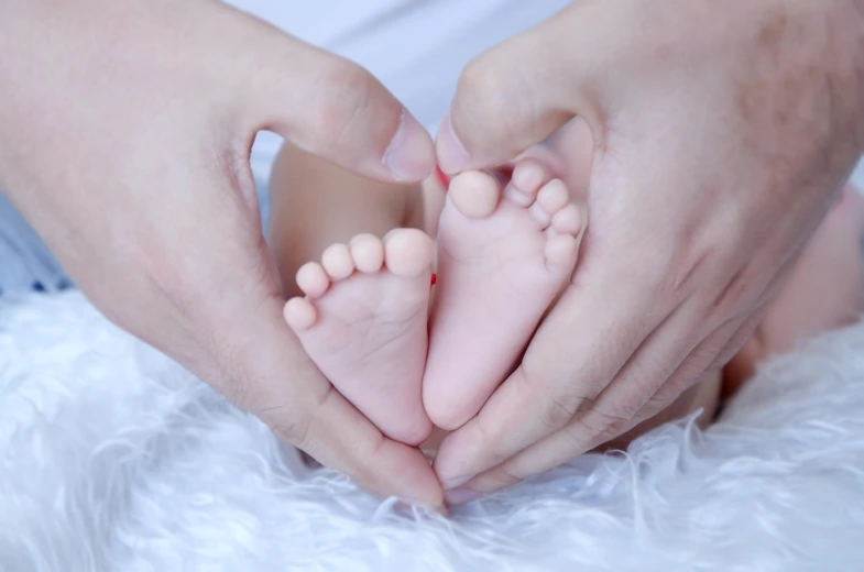 a close up of a person holding a baby's feet, symbolism, avatar image, husband wife and son, soft pads, creating a soft