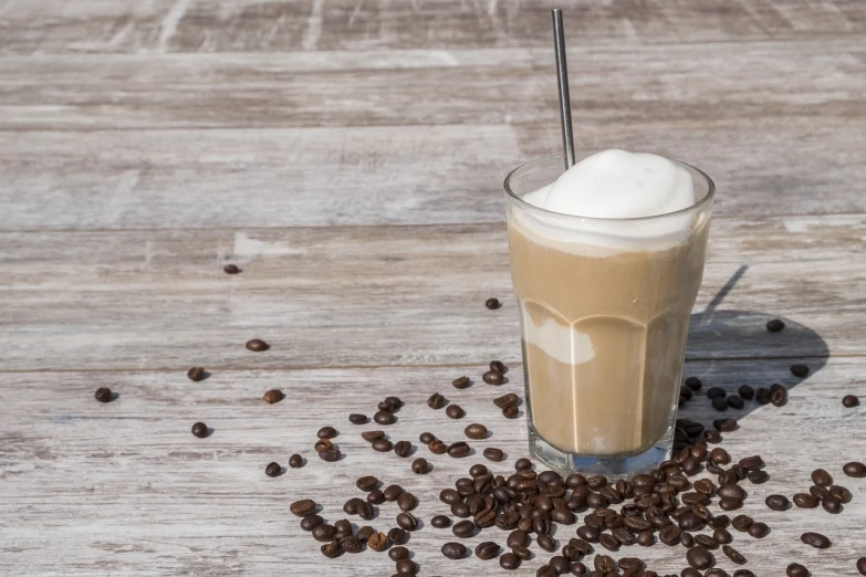 a glass of coffee sitting on top of a wooden table, shutterstock, milkshake, background image, product photo