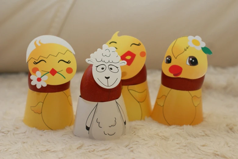 a group of paper dolls sitting on top of a white blanket, inspired by Ei-Q, mingei, egg yolk, sheep, sakimi chan, singing