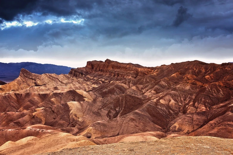 a person standing on top of a mountain under a cloudy sky, a tilt shift photo, by Matthias Weischer, shutterstock, romanticism, death valley, brown canyon background, high detail photo of a deserted, dark