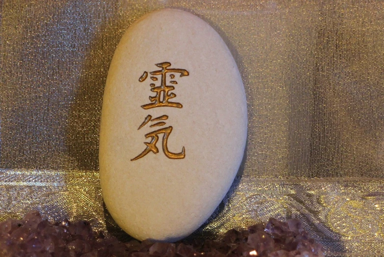 a white stone with a chinese writing on it, a photo, inspired by Kaigetsudō Anchi, flickr, amethyst, golden raito, elemental guardian of life, pink zen style