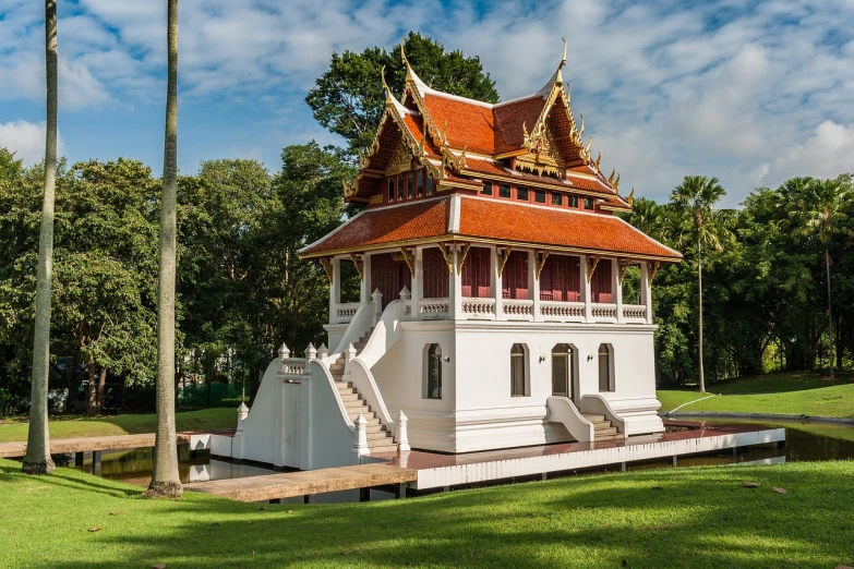 a white building sitting on top of a lush green field, by Bernardino Mei, shutterstock, thai temple, 19th century, brown, persian style architecture