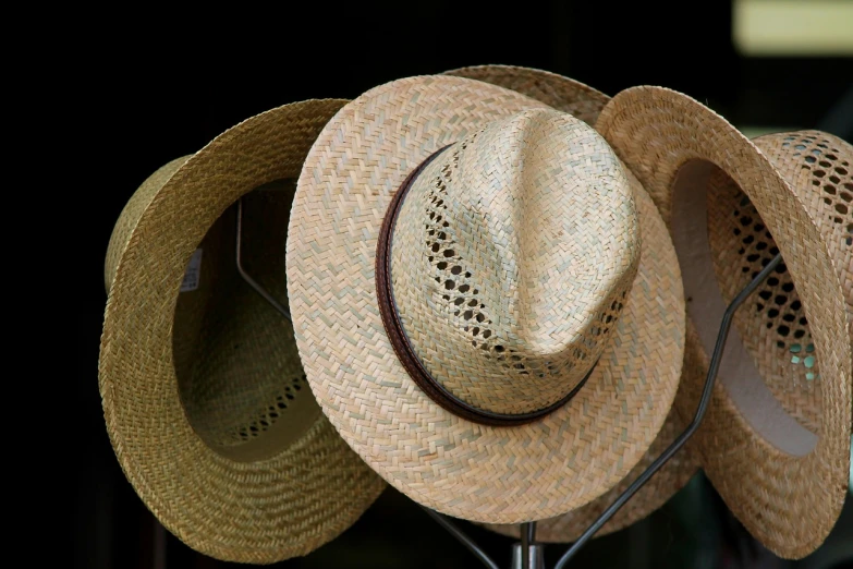 a couple of straw hats sitting on top of a rack, photograph credit: ap, closeup - view, version 3, in a row