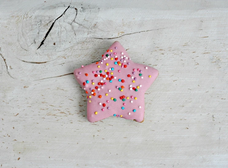 a pink star shaped cookie with sprinkles on it, a picture, folk art, high quality product photo, chocolate, rustic, candy pastel