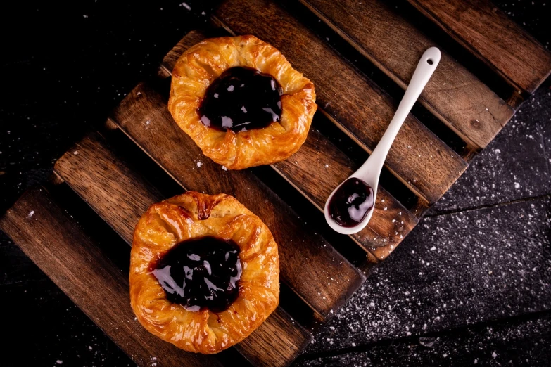 a couple of pastries sitting on top of a wooden cutting board, by Bernardino Mei, shutterstock, baroque, some chocolate sauce, awesome greate composition, stock photo, patagonian