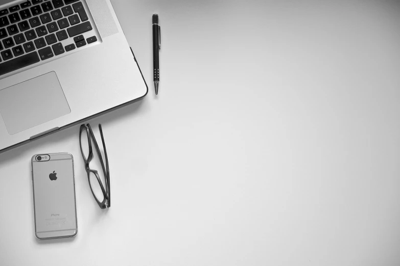 a laptop computer sitting on top of a desk next to a cell phone, a black and white photo, pexels, minimalism, banner, white studio background, devices and instruments, photo taken from above