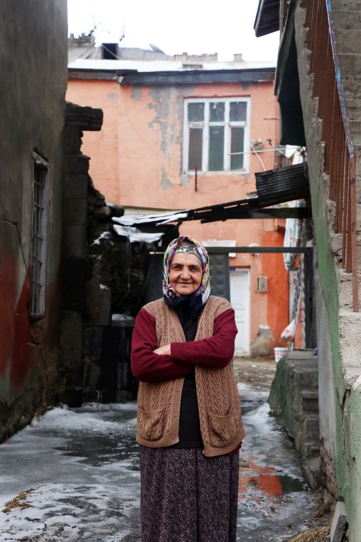 a woman standing in an alley with her arms crossed, a portrait, hurufiyya, can basdogan, grandma, dezeen, february)