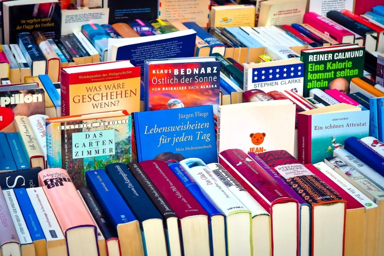 a pile of books sitting on top of a table, a stock photo, by Hans Schwarz, shutterstock, viennese actionism, colored market stand, post processed denoised, munich, advert