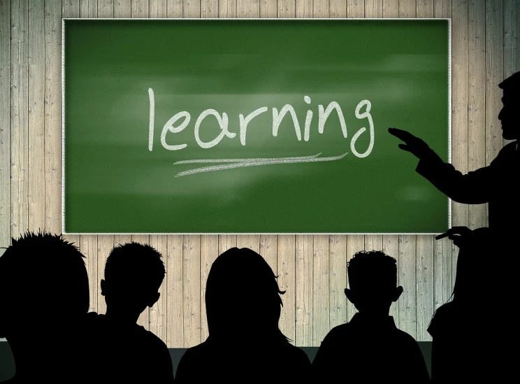 a group of people standing in front of a blackboard with the word learning written on it, a picture, pixabay, sitting in the classroom, silhouettes of people, wooden, looking from shoulder