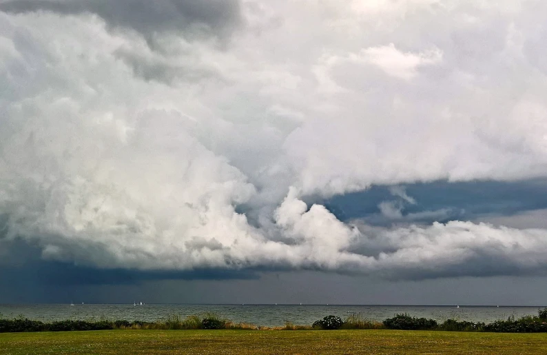 a man flying a kite on top of a lush green field, a picture, by Jan Rustem, a violent storm at sea, ceremonial clouds, panorama, ((oversaturated))