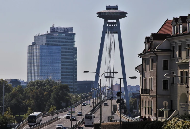 a street filled with lots of traffic next to tall buildings, a picture, by Oskar Lüthy, flickr, tall bridge with city on top, flying saucer, warsaw, espoo