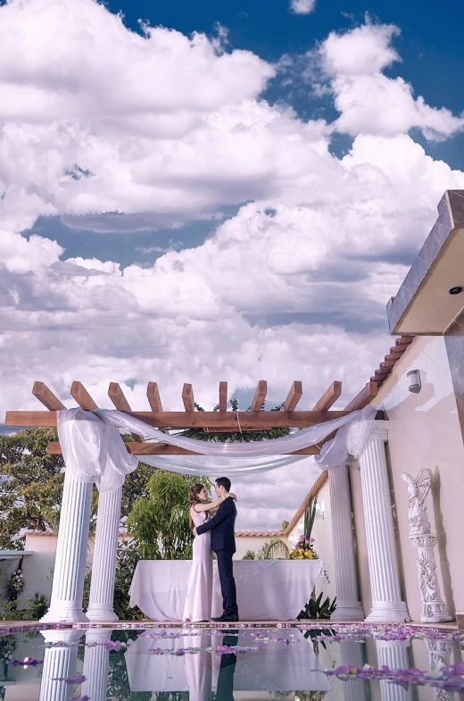 a bride and groom standing in front of a pool, a colorized photo, by Juan O'Gorman, unsplash, panorama view of the sky, canopies, clay, roof garden