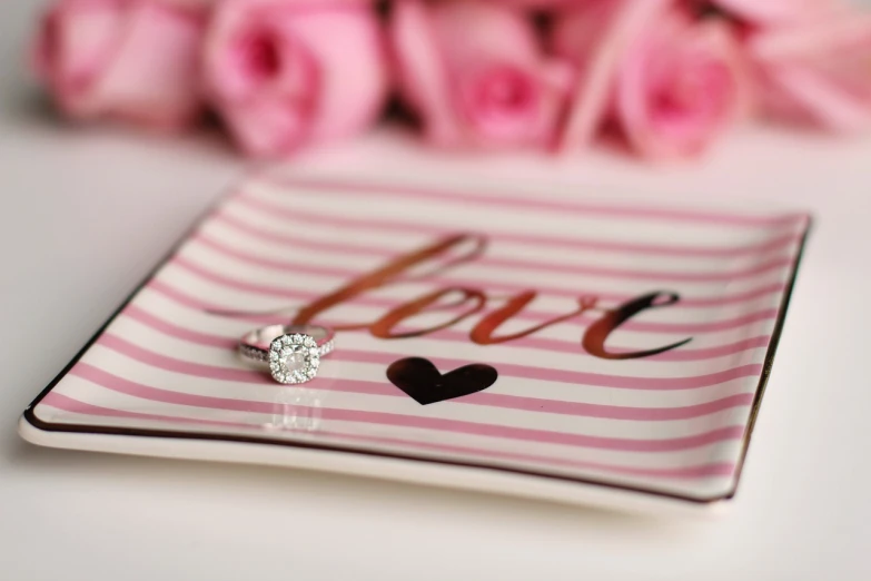 a close up of a plate with a ring on it, a picture, pink hearts in the background, high quality], a beautiful mine, striped