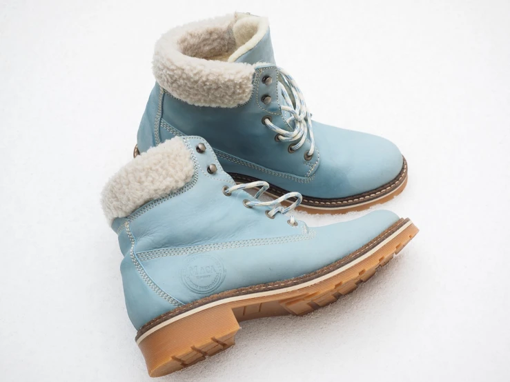 a pair of blue boots sitting on top of a snow covered ground, a pastel, highly detailed product photo, leather shoes, creamy, closeup photo