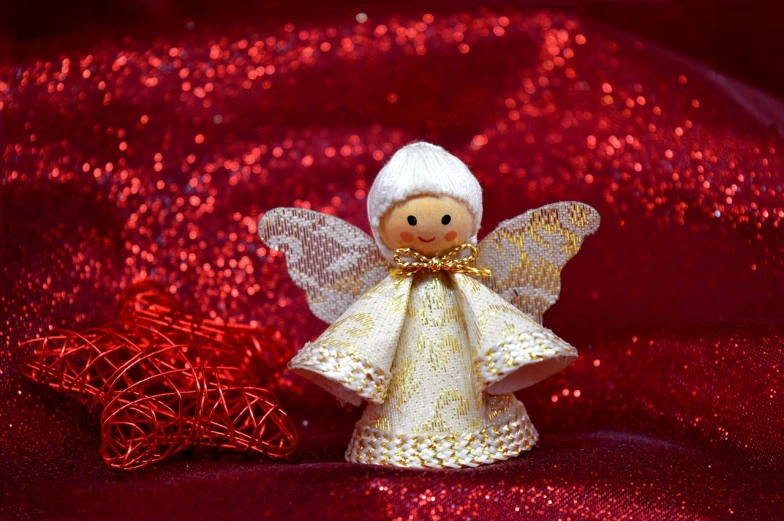 a close up of a figurine of an angel on a red cloth, pexels, folk art, dressed in a beautiful white, shiny and sparkling, cute funny figurine wooden, warm smile