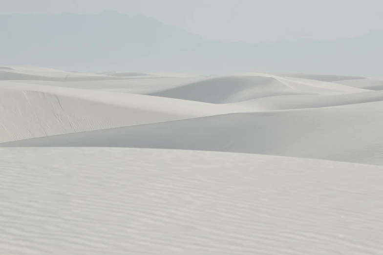 a man riding a snowboard down a snow covered slope, inspired by Georgia O'Keeffe, minimalism, in the desert beside the gulf, usa-sep 20, lots of white cotton, deserted sand