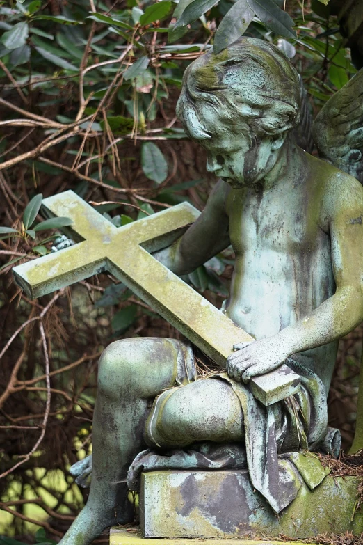 a statue of an angel holding a cross, by Eugeniusz Zak, pixabay, vanitas, discovered in a secret garden, winged boy, reading, moss