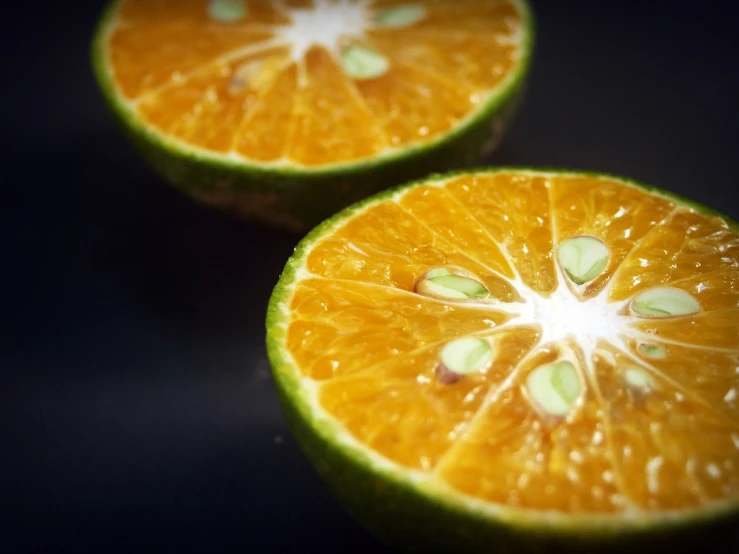 two halves of an orange on a black surface, a macro photograph, shin hanga, bright green dark orange, recipe, umamusume, cinematic shot!