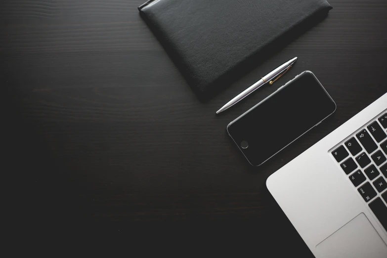 a laptop computer sitting on top of a wooden desk, by Andrei Kolkoutine, pexels, minimalism, black paper, shot on iphone 6, pen and paper, black leather accents