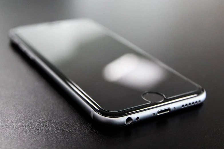 a close up of a cell phone on a table, by Niko Henrichon, uneven glass apple in the dark, sharp nose with rounded edges, product photo, silicone skin