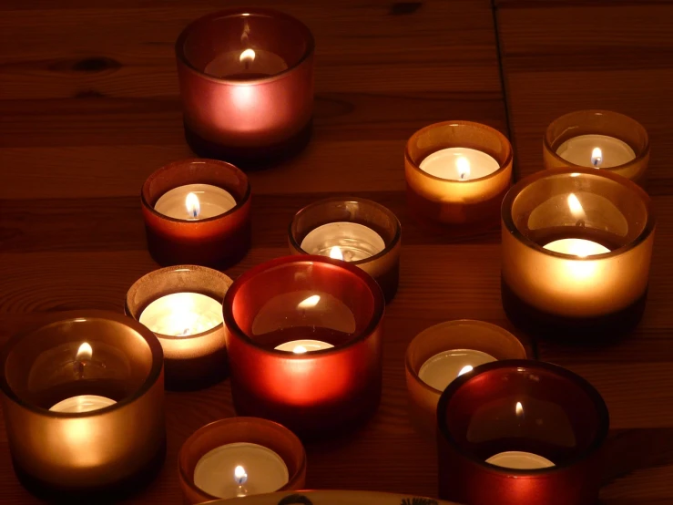 a number of lit candles on a wooden table, by Linda Sutton, high res photo, warm volumetric lights, taken with a pentax1000, various colors