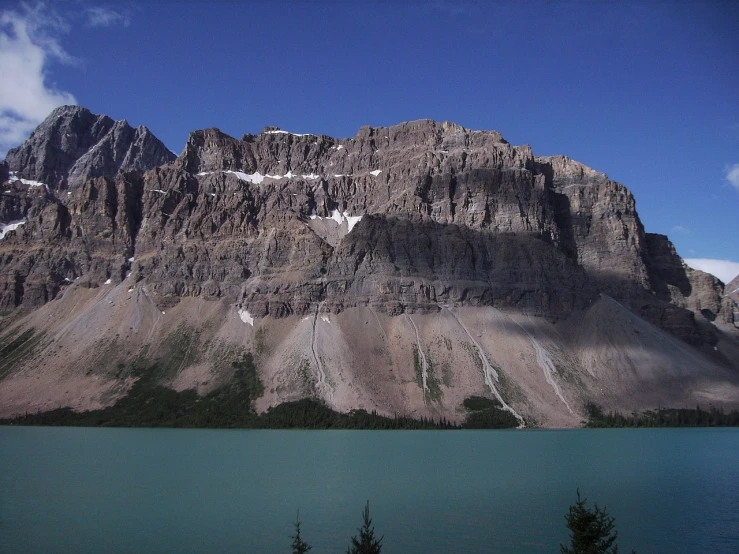 a large mountain towering over a body of water, by Brigette Barrager, flickr, high cliff, lake blue, shot on a 2 0 0 3 camera, award-winnig photo