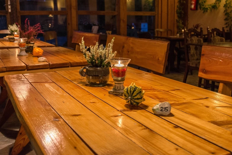 a wooden table topped with vases filled with flowers, by Aleksander Gierymski, shutterstock, candlelit restaurant table, interior of a mountain hut, 2 4 mm iso 8 0 0, rainy evening