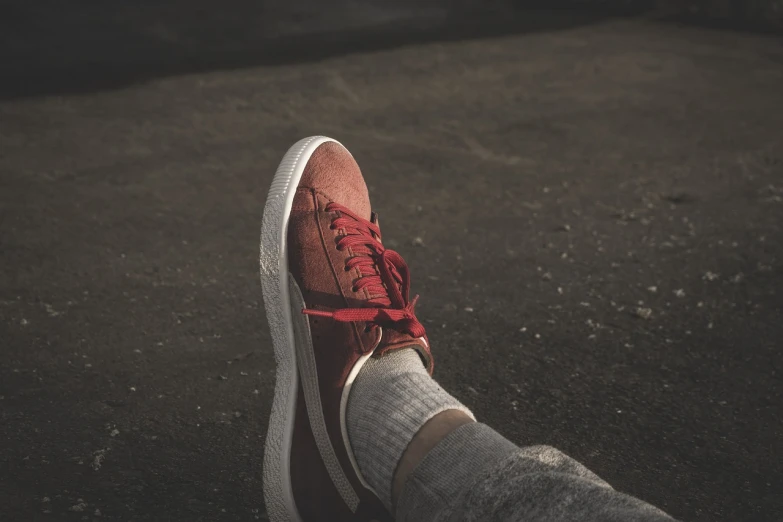 a person's feet in a pair of red sneakers, a picture, realism, atmospheric cool colorgrade, based on a puma, highly detailed product photo, high res photo