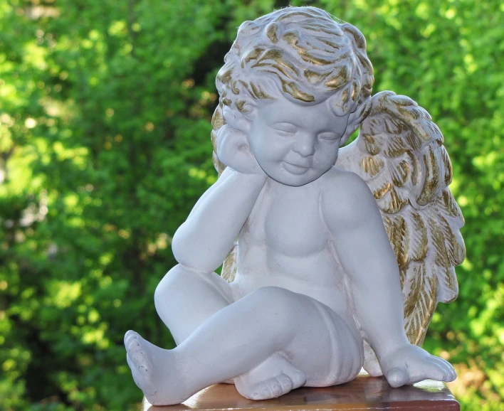 a statue of an angel sitting on top of a wooden post, a statue, baroque, cute decapodiformes, resting on a pillow, high res photo