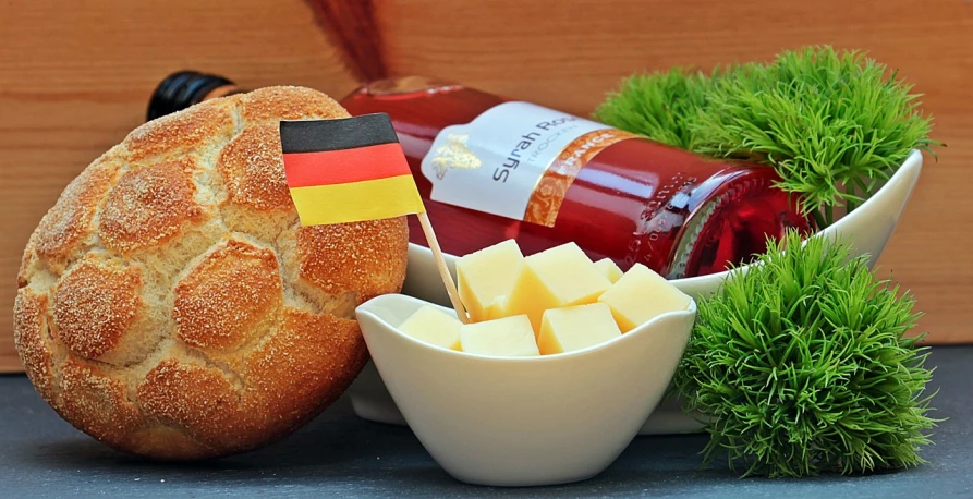 a loaf of bread sitting on top of a table next to a bowl of cheese, a picture, german romanticism, flags, ketchup, profile image, schnapps