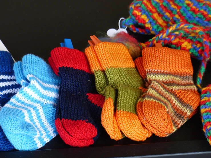 a group of knitted mittens sitting on top of a table, a picture, flickr, full of colour 8-w 1024, toys, striped socks, blue and orange