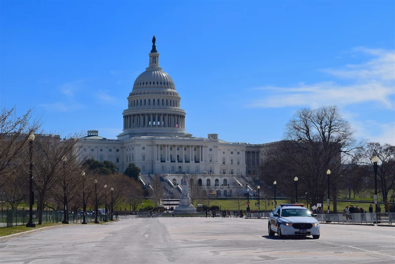 a police car is parked in front of the capitol building, a picture, by Tom Carapic, flickr, compressed jpeg, photo taken in 2 0 2 0, small, neo classical architecture