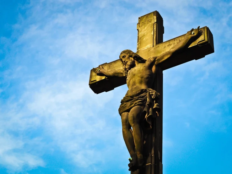 a statue of jesus on a cross against a blue sky, pexels, baroque, istockphoto, on a dark background, stock photo, sacrifice