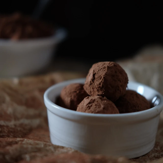 a bowl of chocolate truffles sitting on a table, inspired by Ödön Márffy, renaissance, taken with canon 8 0 d, powder, bottom angle, 2 0 1 4