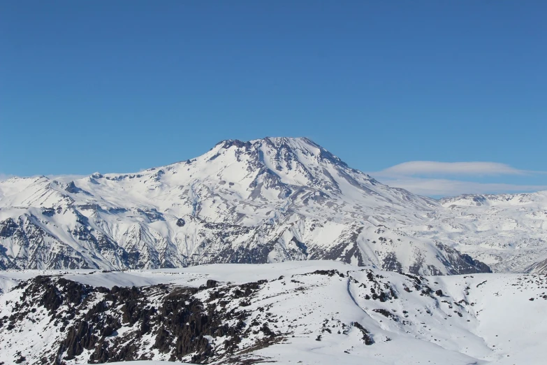 a man riding skis on top of a snow covered slope, flickr, hurufiyya, volcano in the background, chilean, banner, wikimedia commons